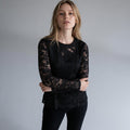 Modella indossa maglietta nera in pizzo XE BLU Abbigliamento Donna con maniche velate e vestibilità aderente